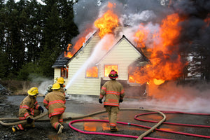 Firefighters actively extinguishing flames on a residential home to demonstrate effective wildfire response techniques.
