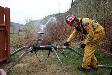 Proudly Canadian-made FireBozz wildfire sprinklers in action protecting a home with wildfire flames in the background